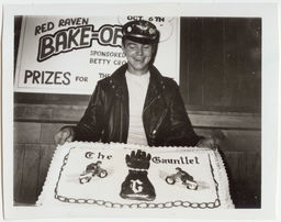Man posing with cake on which is labeled The Gauntlet