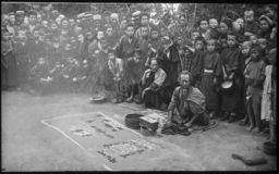 A large crowd surrounding men making sand pictures
