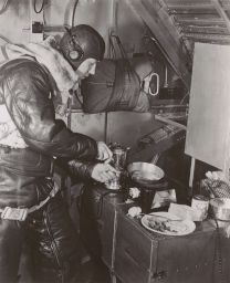 Airman cooking breakfast in airplane galley.