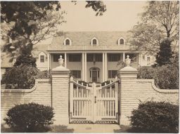 White brick house with columns and fence
