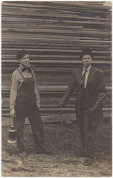 Male impersonators in front of stack of lumber