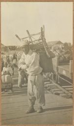 [Korean porter with wicker chair on back]