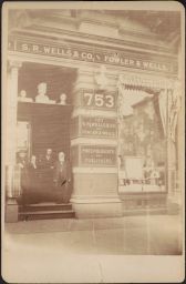 Photograph of Samuel Robert Wells, Charlotte Fowler Wells, and Lorenzo N. Fowler standing in the doorway of S.R. Wells & Co., ca. 1880s?