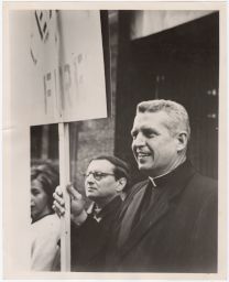 Philip Berrigan holding a protest sign and smiling