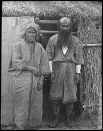 Ainu woman and man at side door of chise