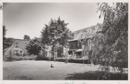 Child sitting on Sunnyside lawn, with more people on the sun porch.