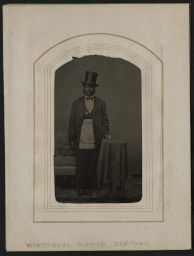 Man in top hat standing by a table