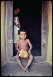Child in doorframe with coconut