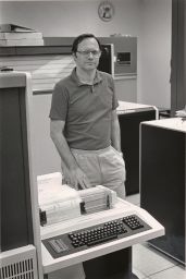 John Abel Standing by a Printer