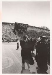 Commencement 1959 in Schoellkopf Field with Mark Steckel holding up a sign that reads THANX EZRA