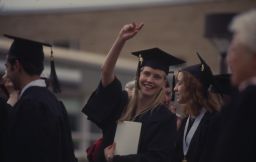 A graduate waves to someone during Commencement
