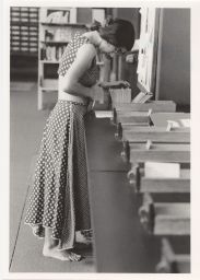 Woman standing in bare feet looking at card catalog