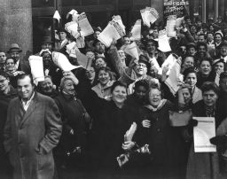 Group of men and women wave General Strike newsletters, 1958.