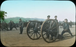 A close-up of Japanese soldiers preparing and lighting cannons in a field