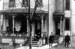 People Standing and Sitting in Front of a House