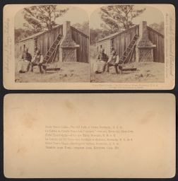 Two adults sitting in front of wooden cabin